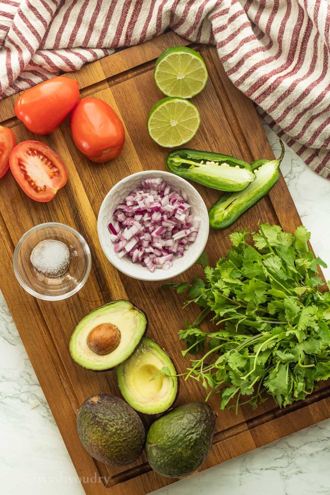 Chopped ingredients for pico de gallo on wood cutting board in glass bowls. 