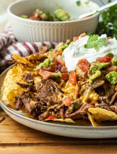 cooked plate full of carne asada nachos on wood cutting board.