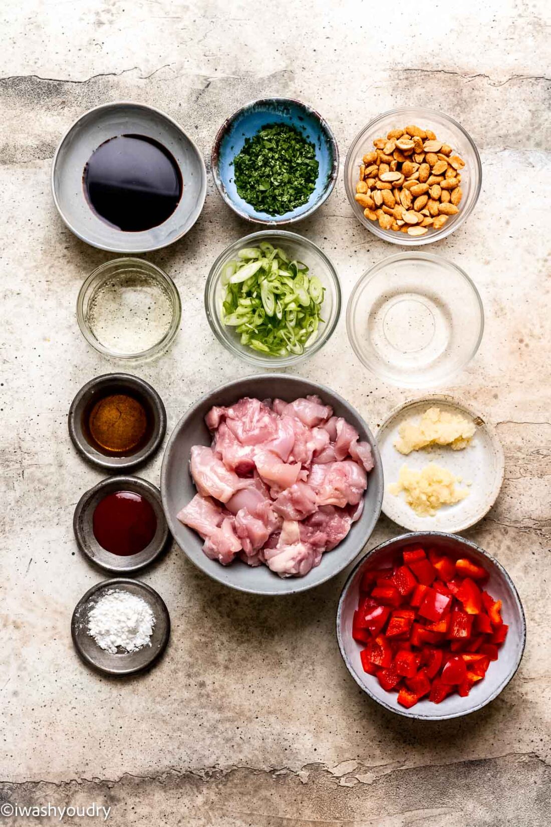 Ingredients for cilantro chicken stir fry in glass bowls on marble countertop. 