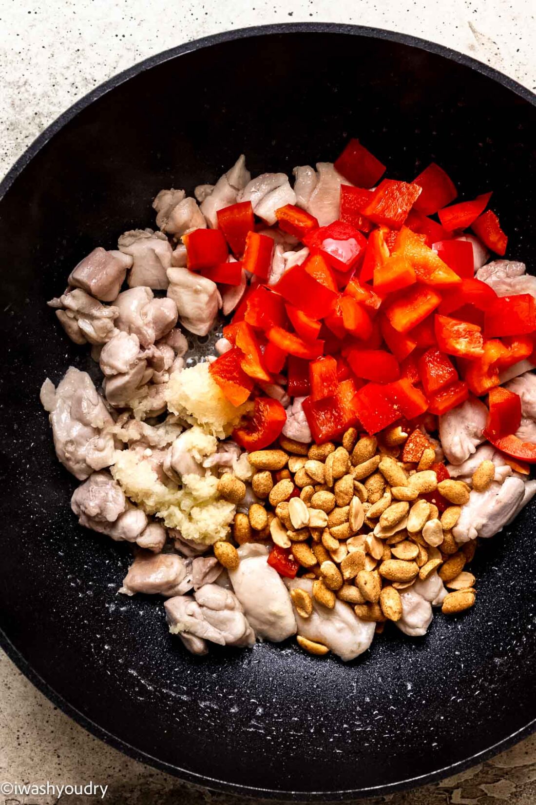 Cooking Raw bell pepper and garlic with chicken and peanuts in wok. 