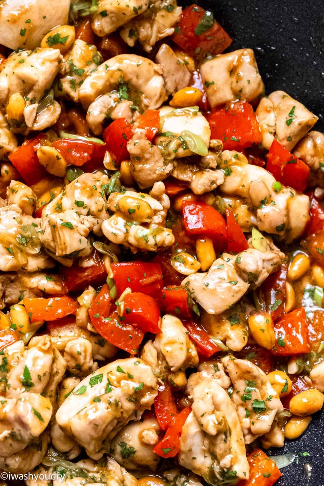 Chicken stir fry with cilantro mixed in sitting in wok. 