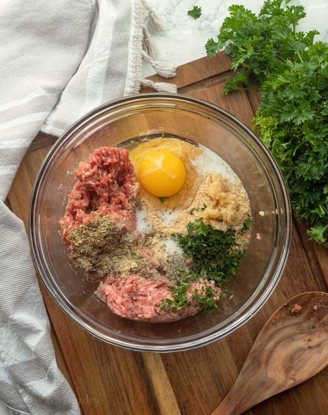 Ingredients for air fryer meatballs combined in a glass bowl.