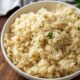 Cooked white rice pilaf in textured white bowl with chopped parsley on top.