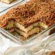 Baked and sliced classic coffee cake in glass pan.