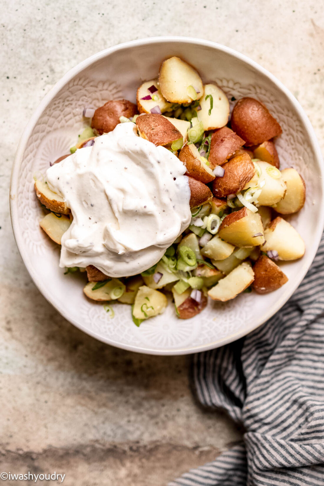 Sauce dolloped onto red potato salad veggies. 