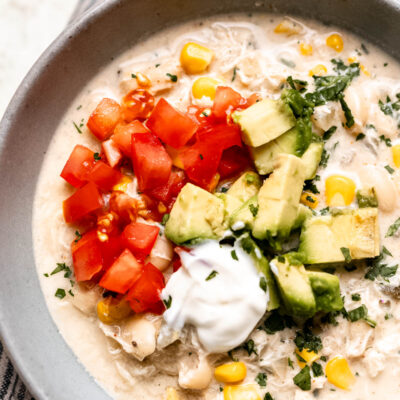 white chicken chili in bowl with tomatoes and avocado.