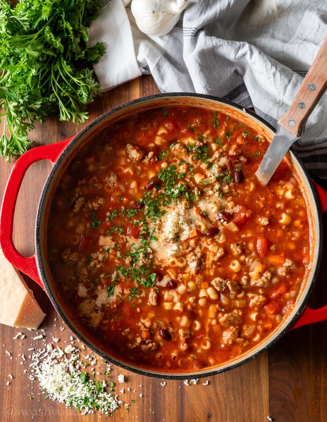 pot of pasta fagioli with ladle and parsley.