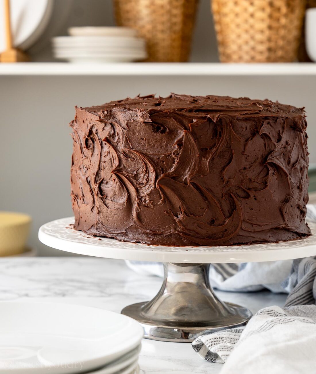 frosted chocolate cake on white platter.