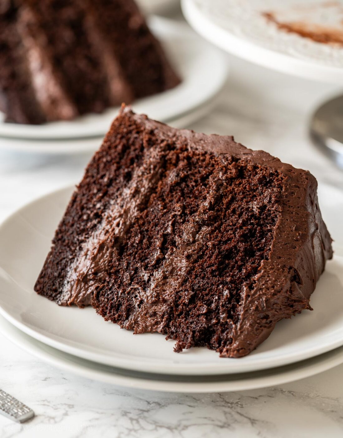 slice of chocolate cake laying on it's side on a white plate. 