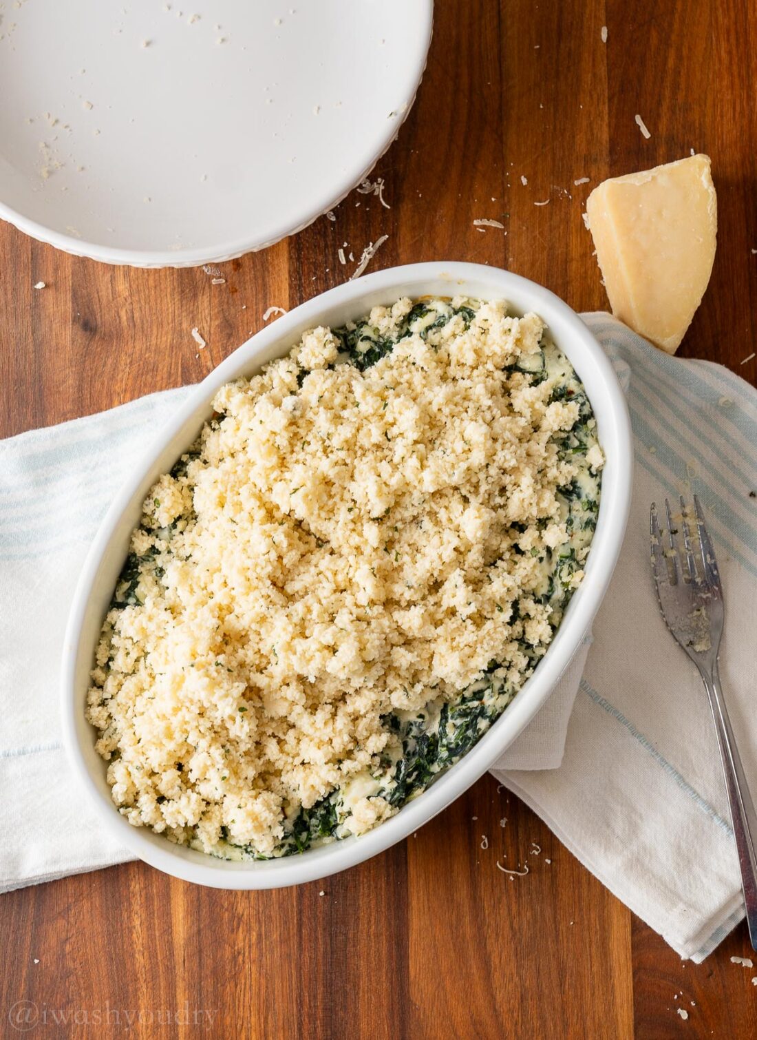 spinach dip topped with parmesan cheese topping before being baked.