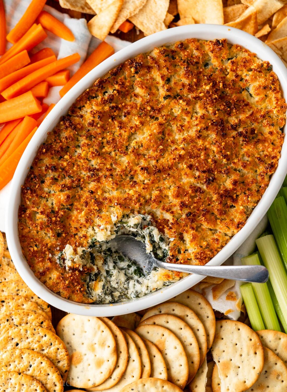 white dish filled with warm spinach dip and topped with crispy parmesan bread crumbs.
