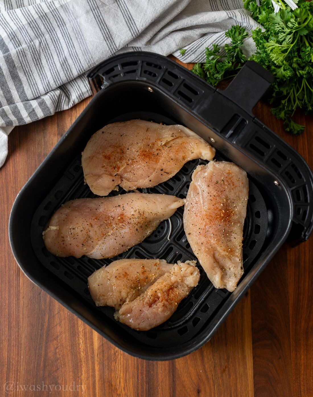 Raw Chicken in air fryer basket.