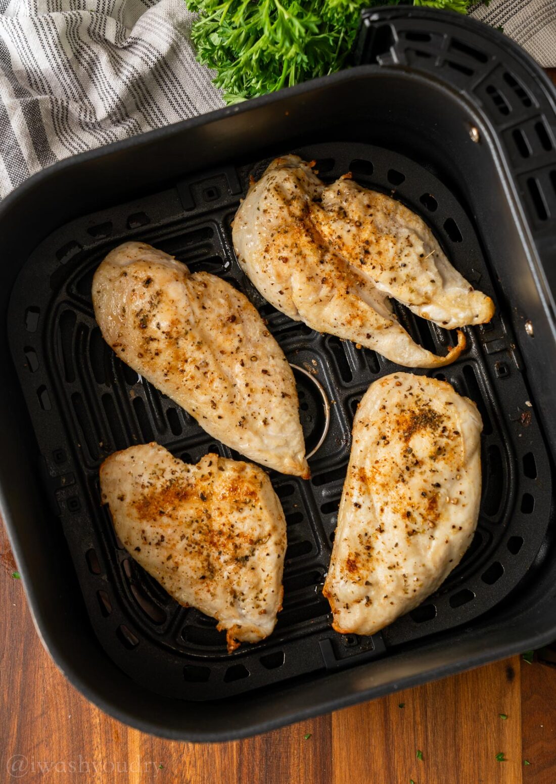 Cooked chicken in air fryer basket.