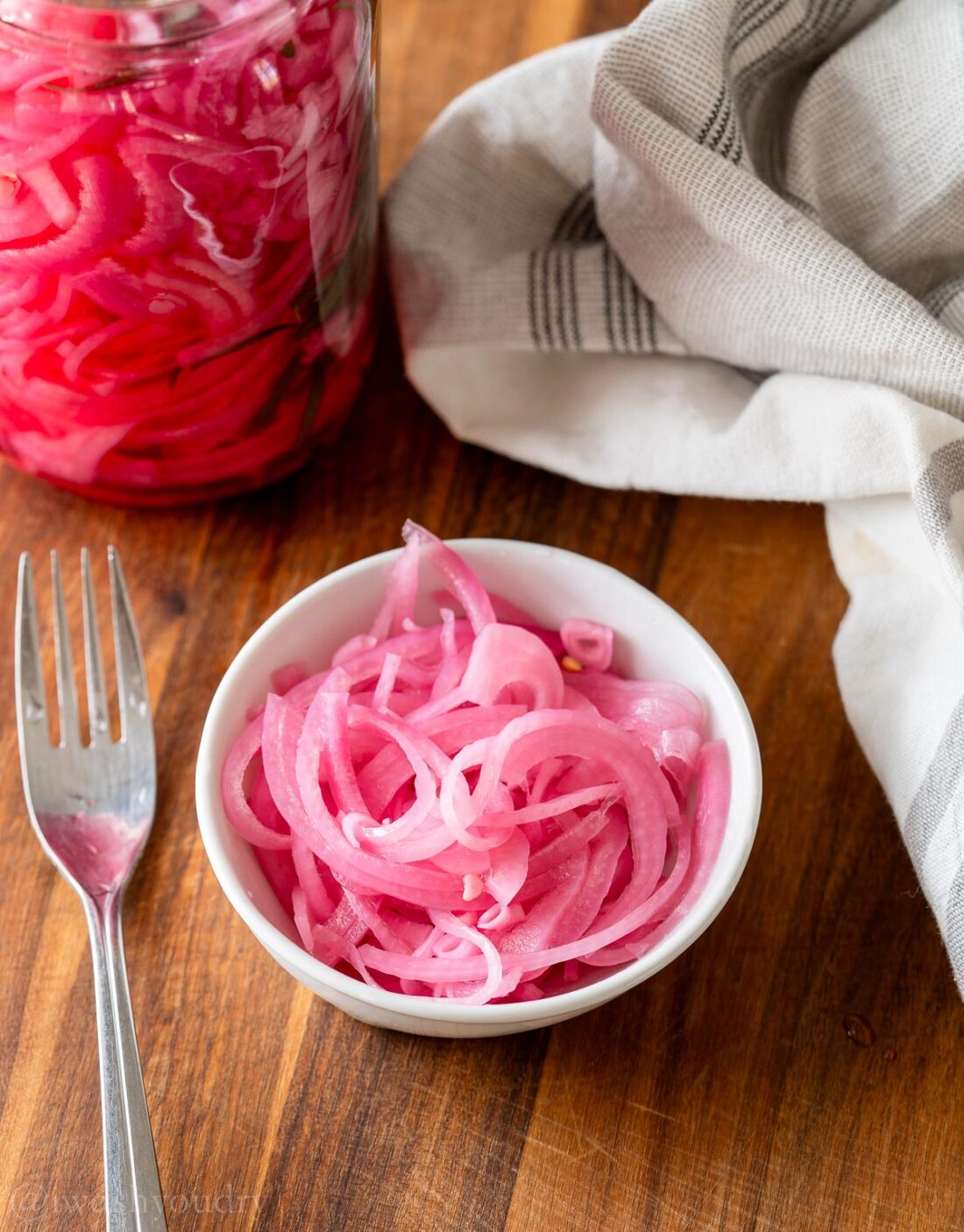 Bowl of pickled onions on cutting board. 