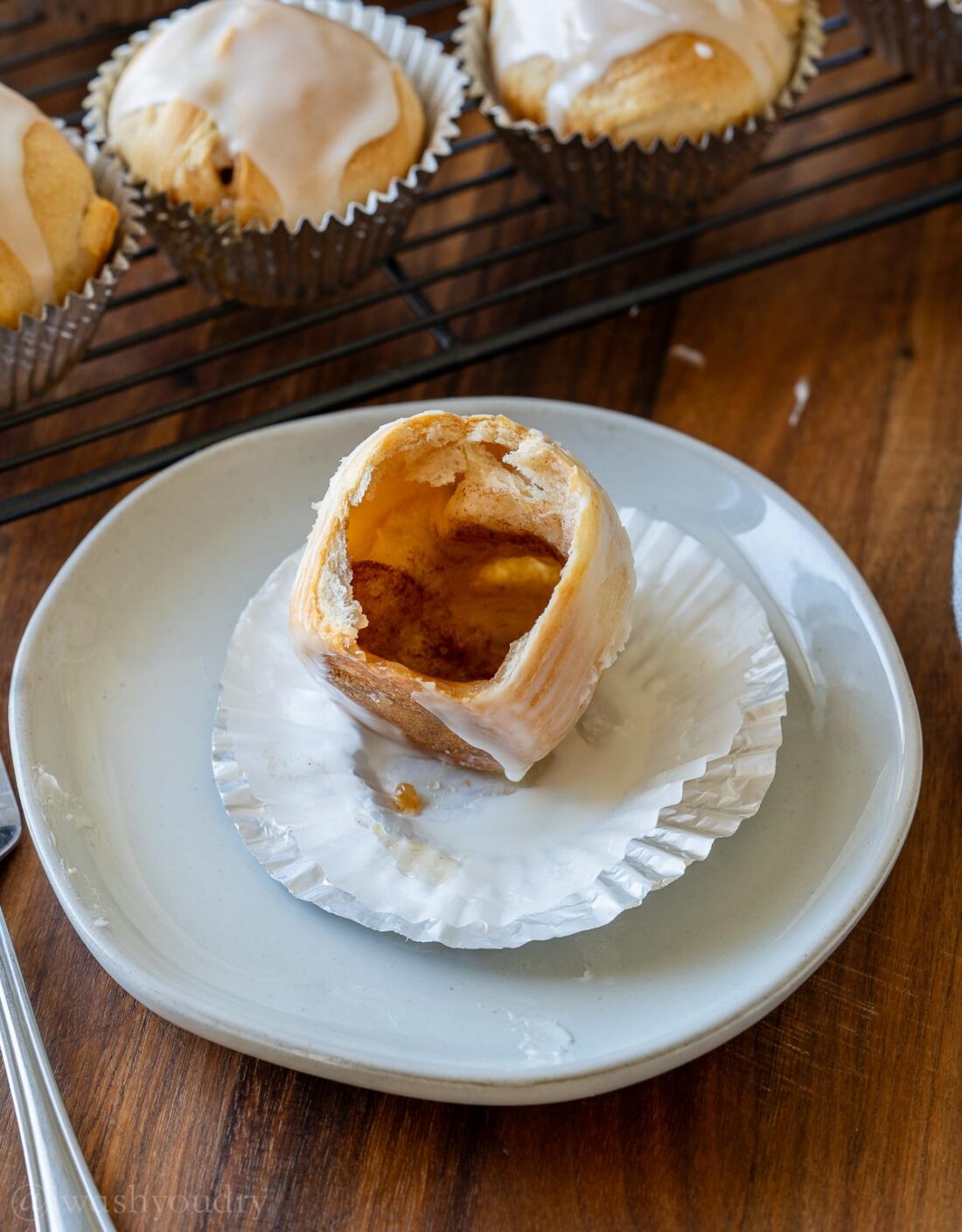 flakey crescent roll on white plate, that is baked and showing an open, hollow center.