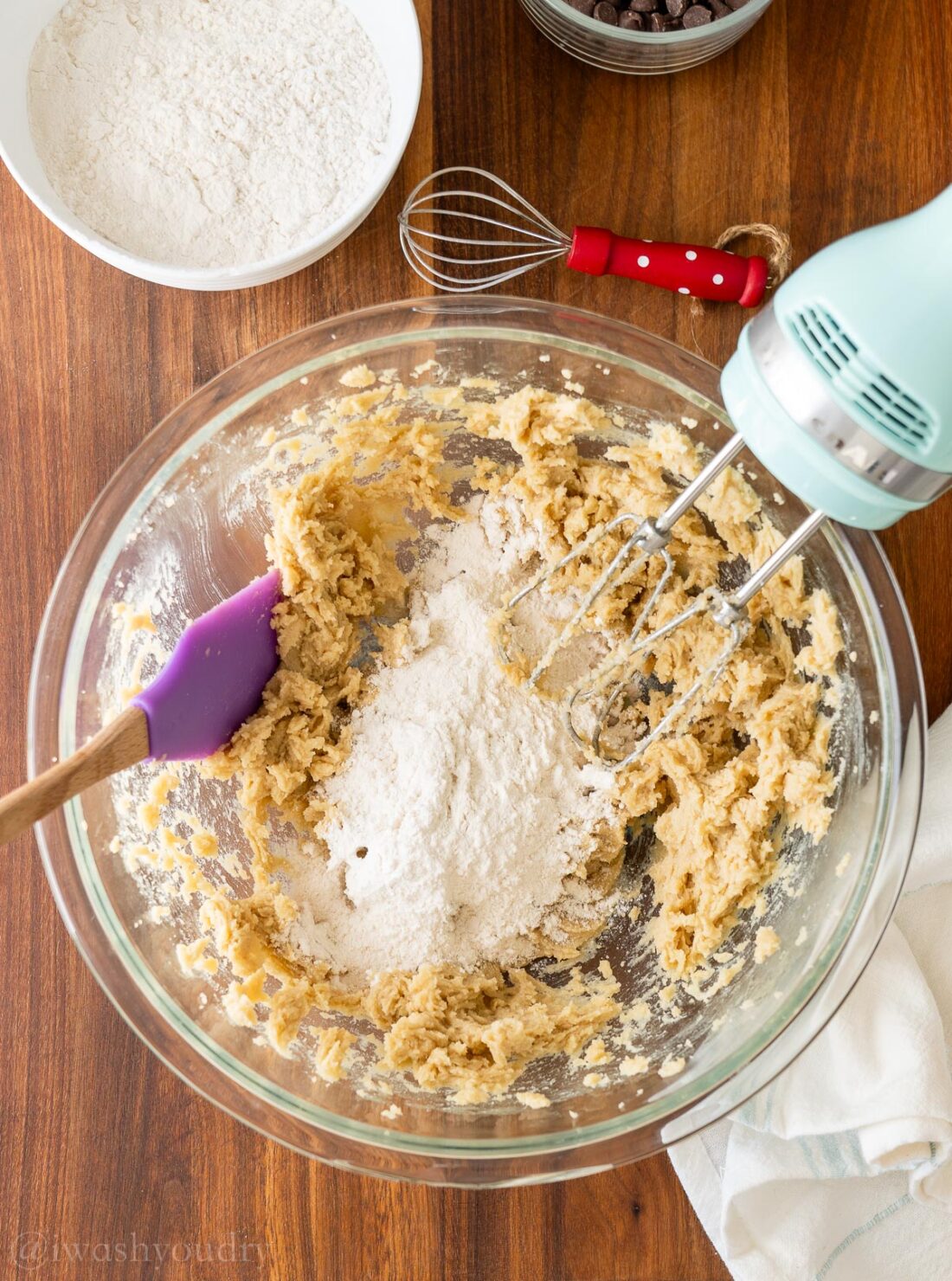 adding flour and other dry ingredients to mixing bowl with rubber spatula.