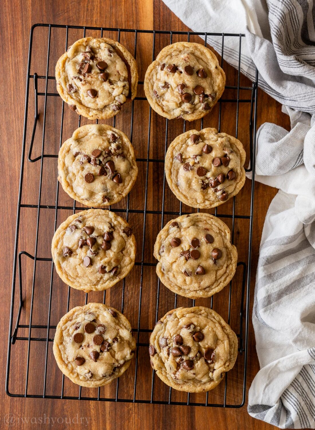 chocolate chip cookies on wire rack with towel nearby.