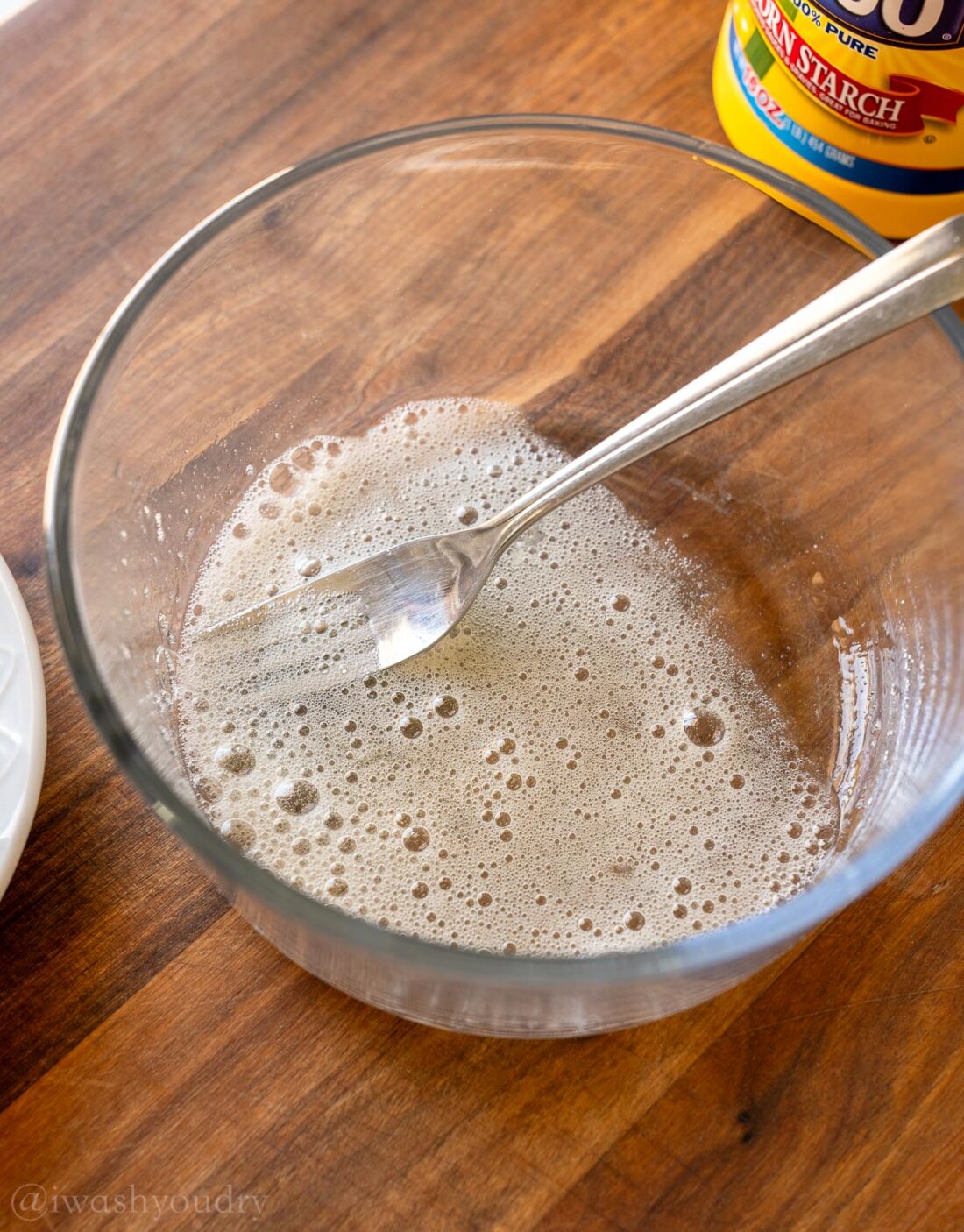 Frothy egg whites in bowl with fork.