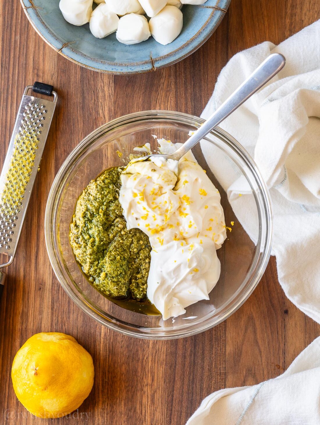 Creamy pesto sauce with lemon and sour cream in a glass dish.