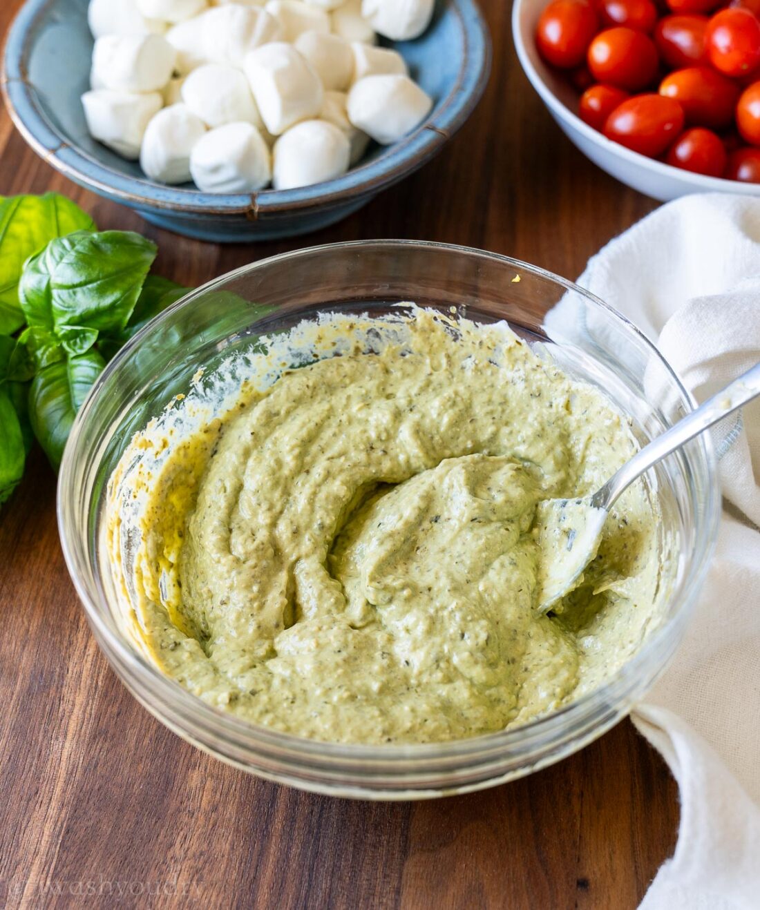 creamy pesto sauce in a glass bowl with spoon.