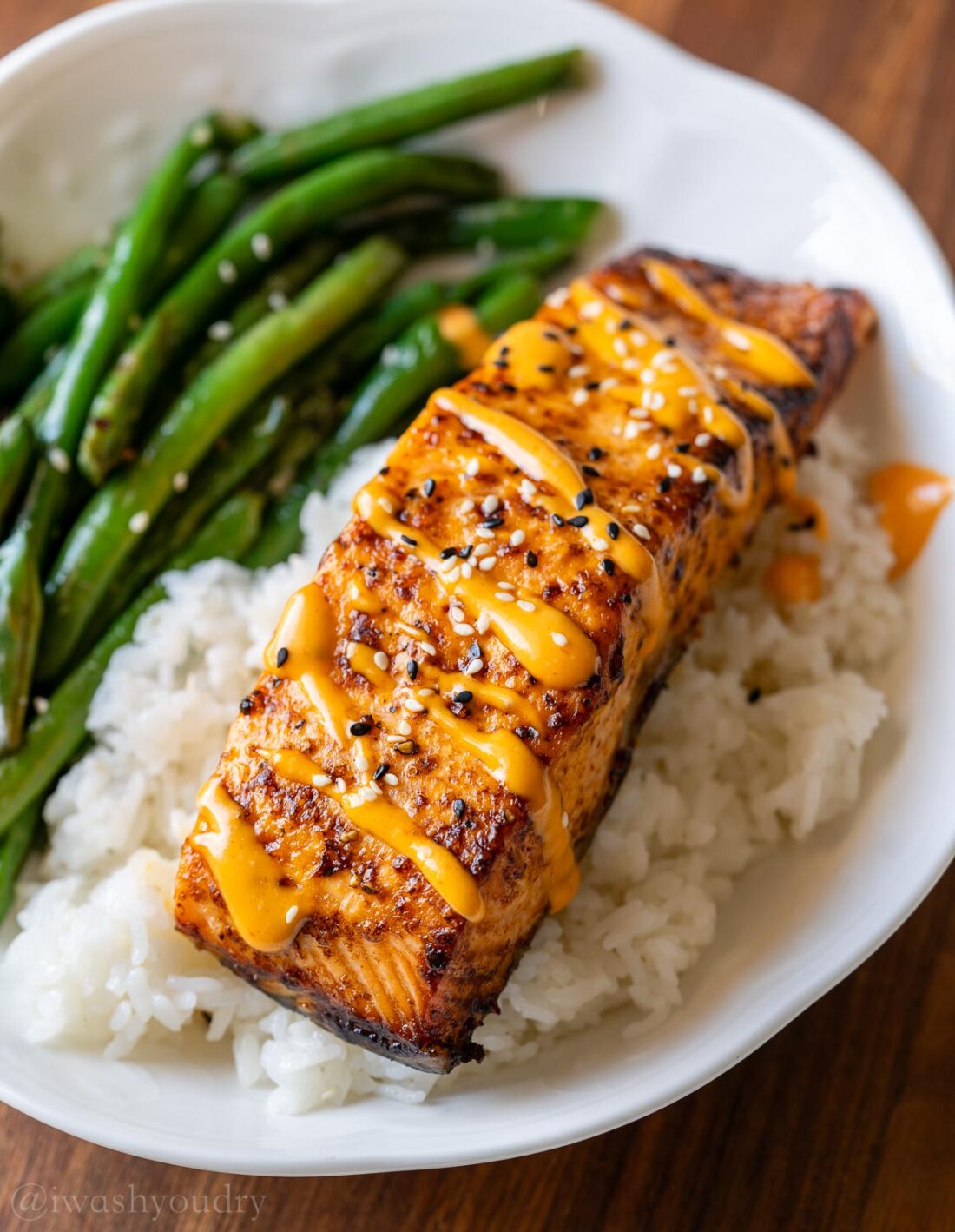 spicy salmon on top of white rice with a side of green beans.