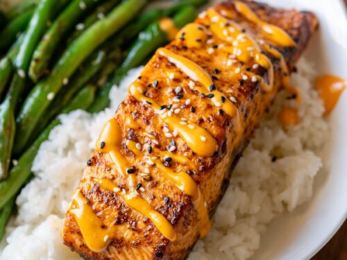 spicy salmon on top of white rice with a side of green beans.