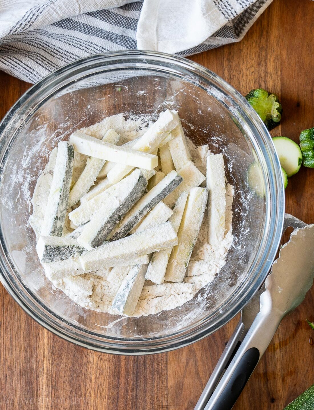 zucchini sticks in glass bowl with flour.