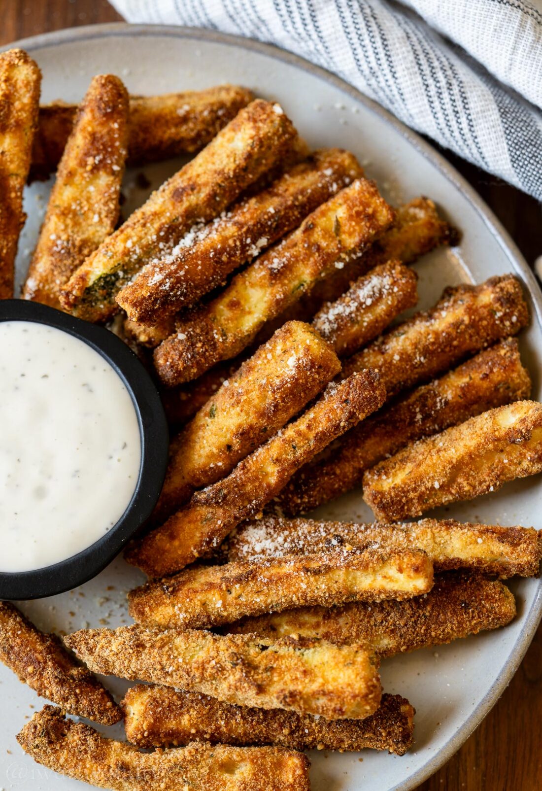 zucchini sticks on a gray plate with a side of ranch dressing.