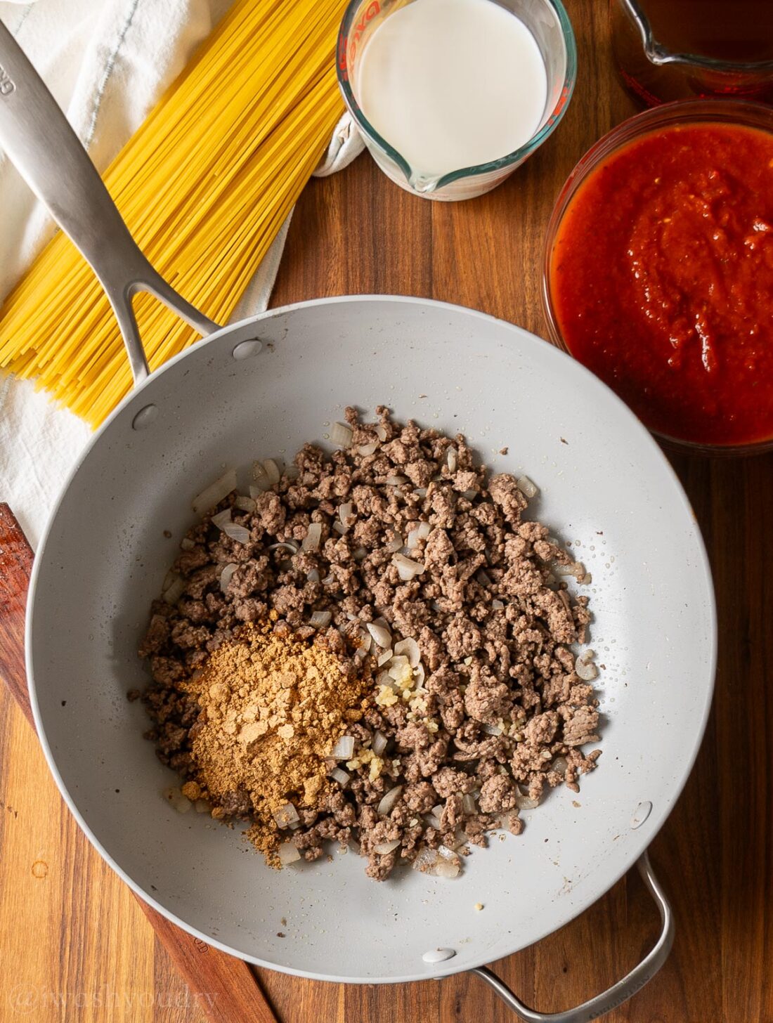 browned ground beef in skillet with seasonings on top.