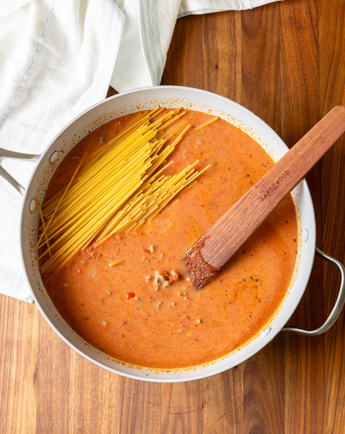 saucy beef mixture with spaghetti noodles and wooden spoon.