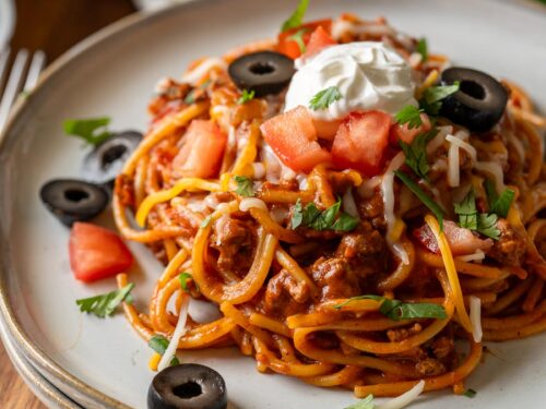 plate of spaghetti with taco meat and toppings.